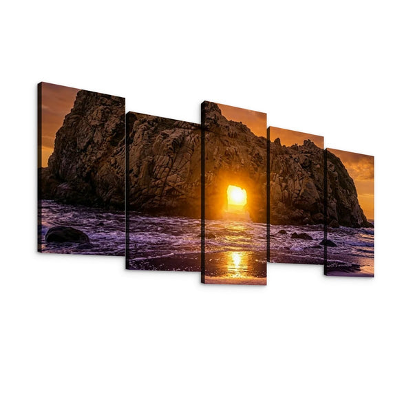 Five-panel canvas wall art showing a rocky coastal sunset with waves, displayed against a plain white background.