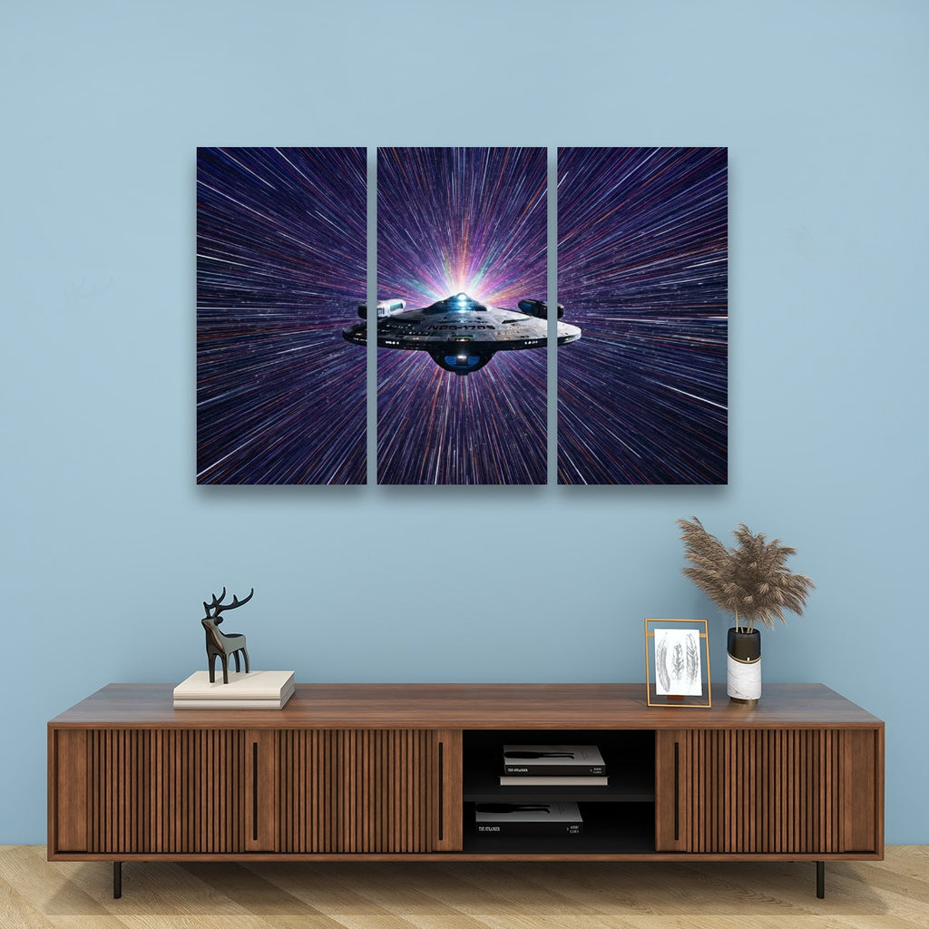 A three-panel canvas wall art set depicting a spaceship in a purple and blue starburst galaxy, displayed on a light blue wall above a wooden console table with decorative items.