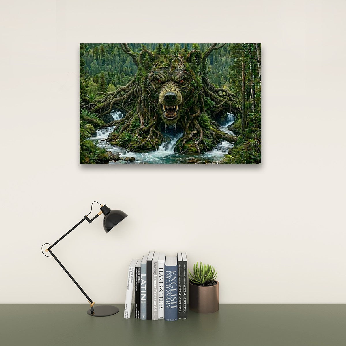 A rectangular wall art print showing a forest stream with a large tree-root bear head, displayed above a desk with a black lamp, books, and a small succulent against a light beige wall.