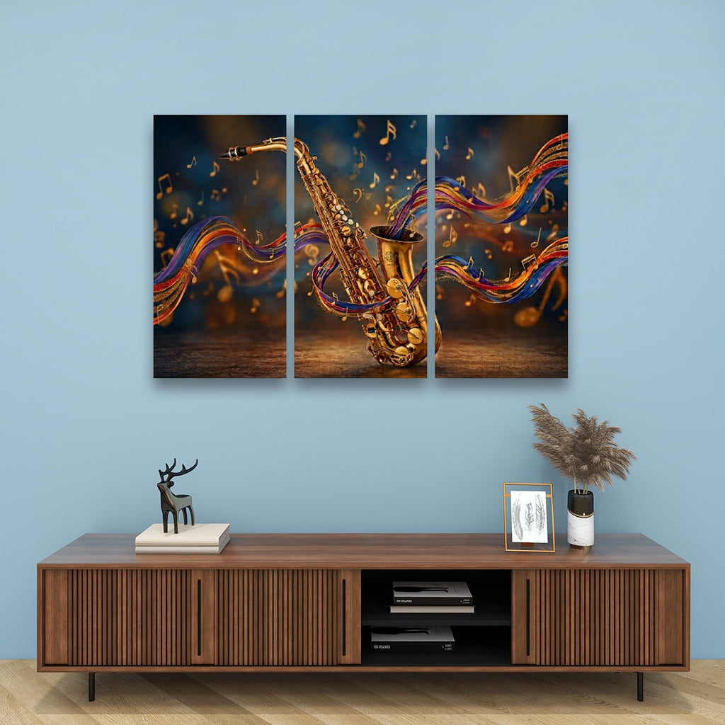 A three-panel canvas wall art set depicting a golden saxophone with colorful flowing musical notes, displayed on a light blue wall above a wooden console table with decorative items.