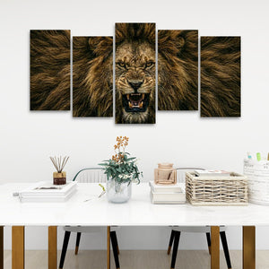 A five-panel canvas wall art set depicting a roaring lion's face and mane, displayed on a white wall above a styled dining table with books, a vase, and a basket.