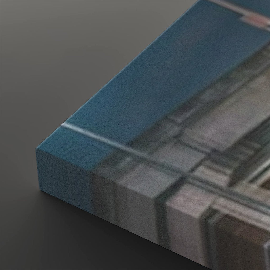 A close-up of a rectangular acrylic or glass art print block with a blue top surface and a blurred architectural or abstract scene printed on the side, resting on a dark gray surface.