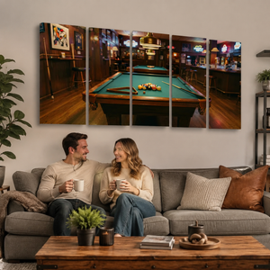 A five-panel canvas wall art set depicting a cozy bar scene with a pool table, shown hanging above a gray sofa with a couple sitting in a living room.