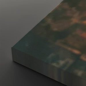 A close-up of a rectangular canvas or print showing an abstract landscape-like scene in muted teal, brown, and orange tones, photographed on a dark gray background.