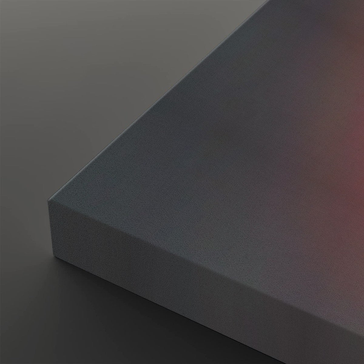 A close-up of a matte gray rectangular panel or block showing its corner and a subtle warm pinkish reflection on one side, set against a matching gray background.