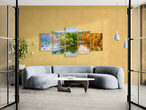 Modern living room with a yellow wall featuring four landscape paintings and a gray sofa.