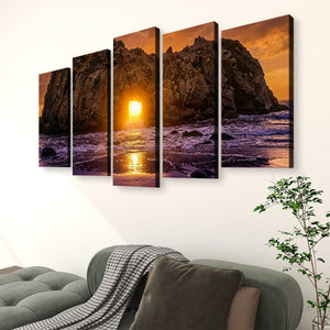 A five-panel canvas wall art set depicting a dramatic rocky coastline at sunset, displayed above a green sofa in a modern living room setting.