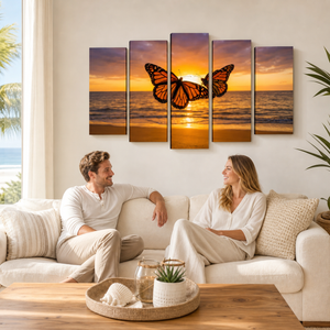 A five-panel canvas wall art set depicting a monarch butterfly over a sunset ocean, displayed on a beige wall above a white sofa with a couple sitting on it in a bright, modern living room.