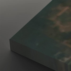 A close-up of a rectangular canvas or print showing an abstract landscape-like scene in muted teal, green, brown, and gray tones, photographed against a dark gray background.