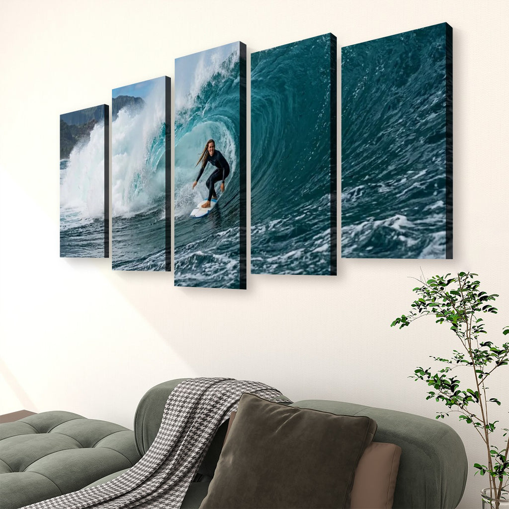 A five-panel canvas wall art set depicting a surfer riding a large blue ocean wave, displayed on a light beige wall above a green sofa with a throw blanket and a potted plant.