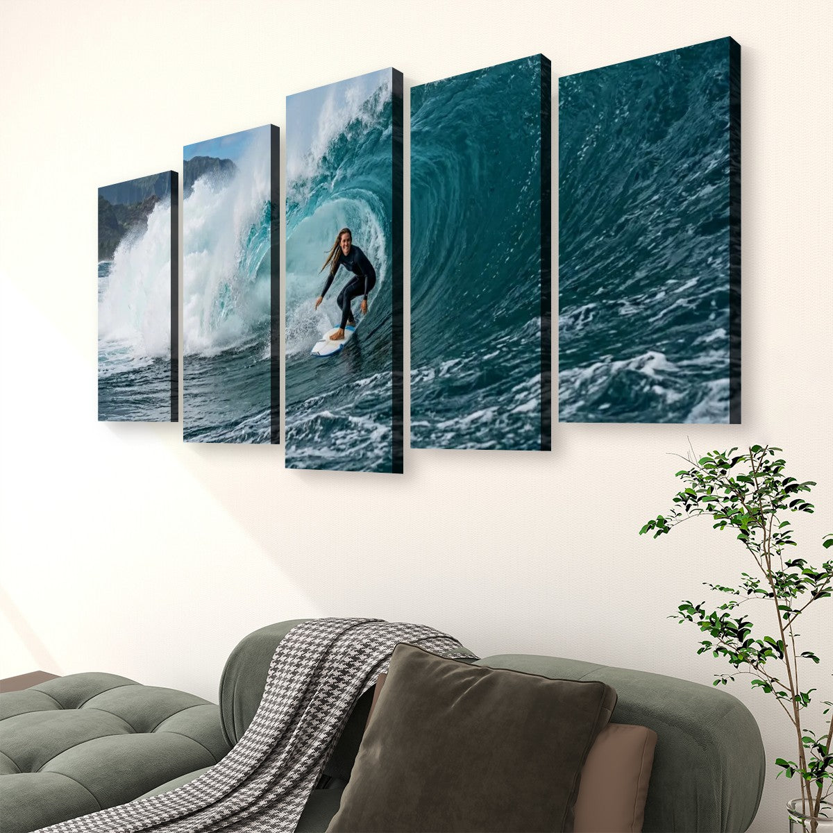 A five-panel canvas wall art set depicting a surfer riding a large blue ocean wave, displayed on a light beige wall above a green sofa with a throw blanket and a potted plant.