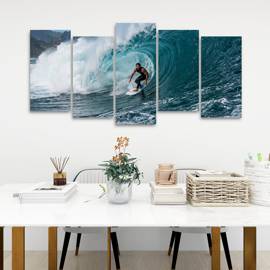 A five-panel canvas wall art set depicting a surfer riding a large blue wave, displayed on a white wall above a styled dining table with books, a vase, and baskets.
