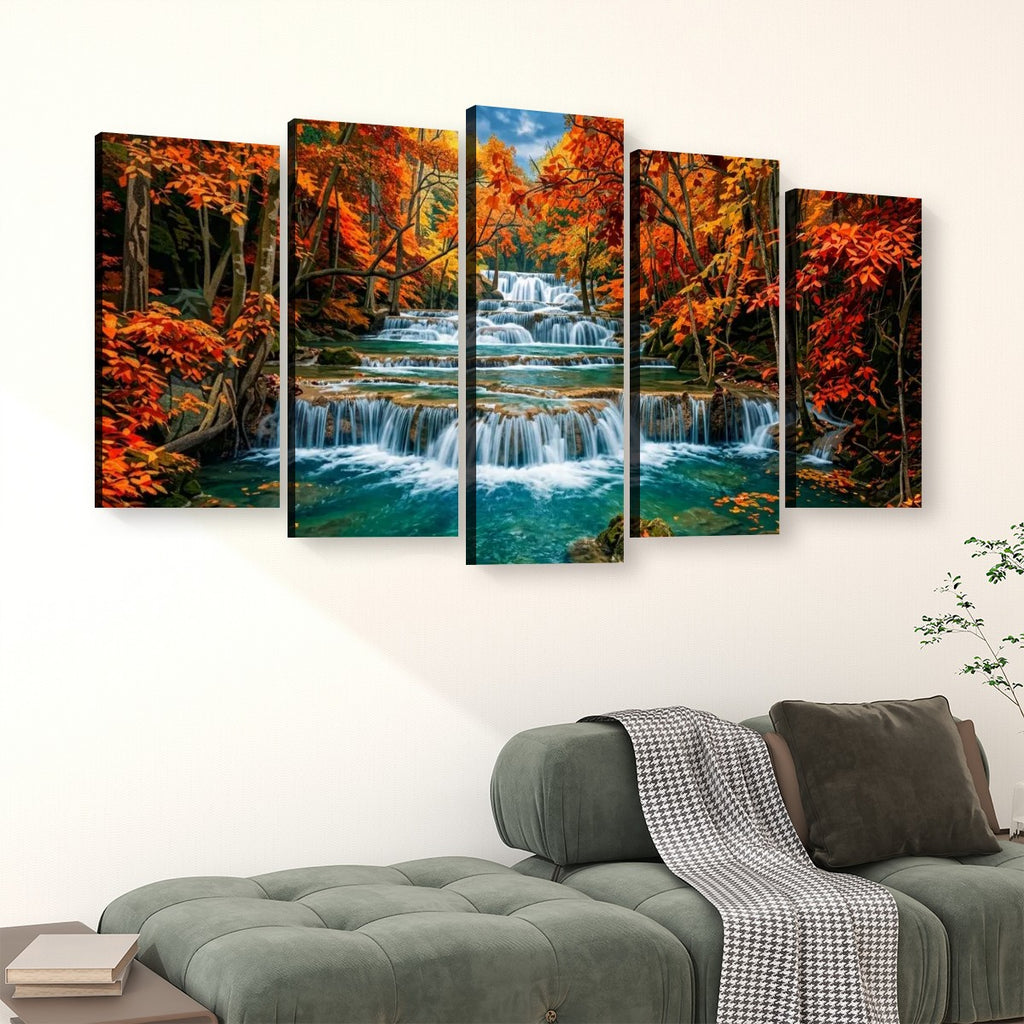 A five-panel canvas wall art set depicting a colorful autumn forest Huay Mae Khamin Falls, displayed on a white wall above a green sofa.