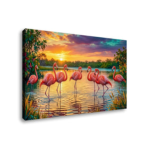 A rectangular canvas wall art print showing a group of pink flamingos standing in shallow water at sunset, with colorful sky, trees, and reflections. The canvas is photographed at a slight angle against a plain white background.