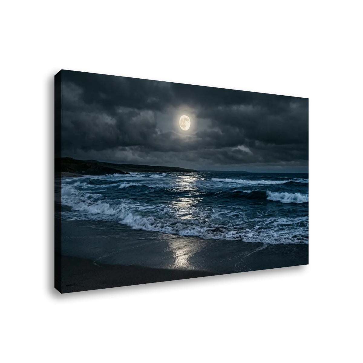 A rectangular canvas wall art print showing a dramatic seascape at night under a full moon, with dark storm clouds, blue-gray waves, and wet sand reflecting light. The canvas is photographed at a slight angle against a plain white background.