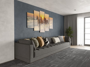 Gray sofa with decorative pillows in a living room with wall art of horses.
