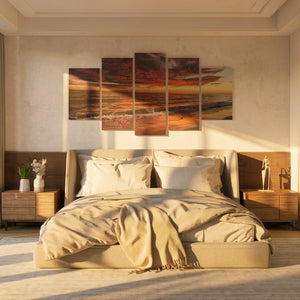 Beige bedroom with a large bed, side tables, and wall art depicting a sunset over water.