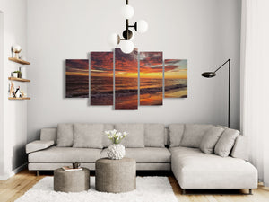 Modern living room with a sectional sofa, coffee table, and wall art depicting a sunset.