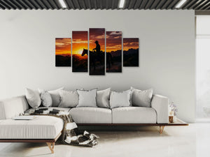 Five-panel wall art of a sunset scene with a horse and rider on a white wall above a sofa.