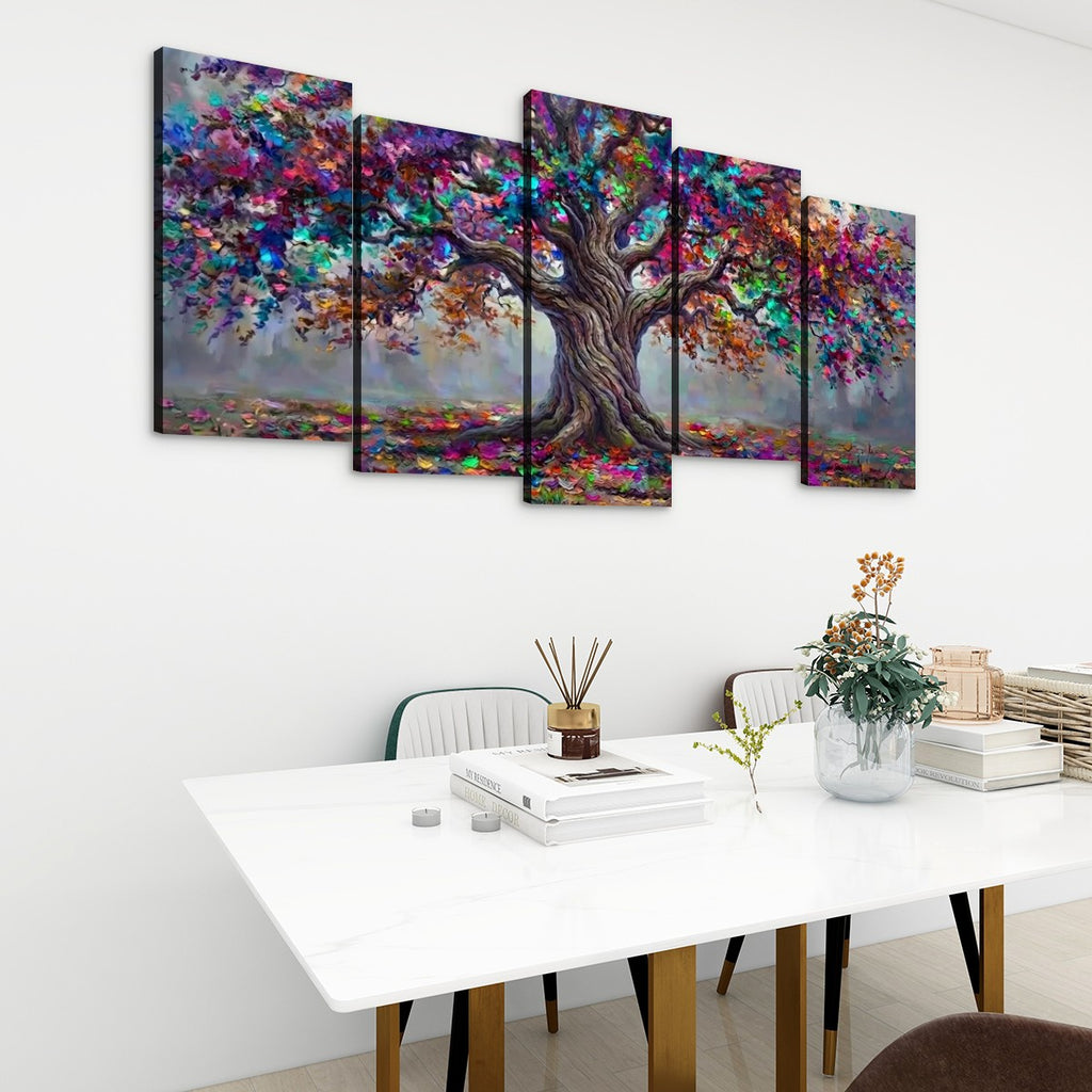 A 5-panel canvas wall art set depicting a colorful, painterly tree with a gnarled trunk, displayed on a white wall above a modern white dining table with books and a vase.