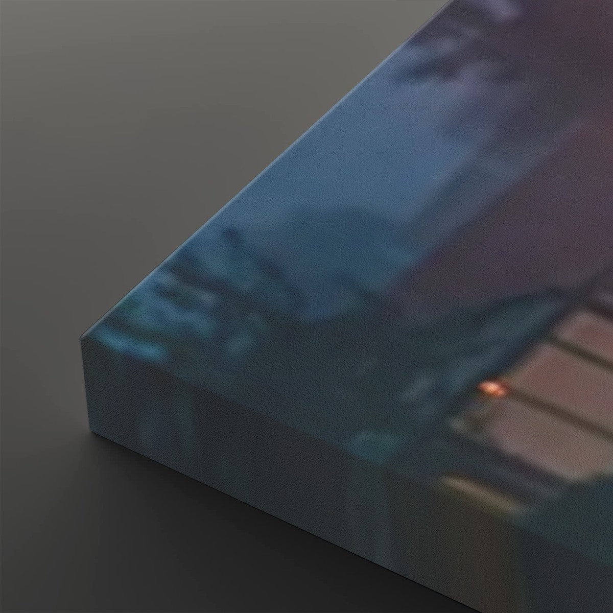 A close-up of a rectangular canvas or block with a printed abstract scene in blue, teal, and purple tones, photographed on a dark gray background.