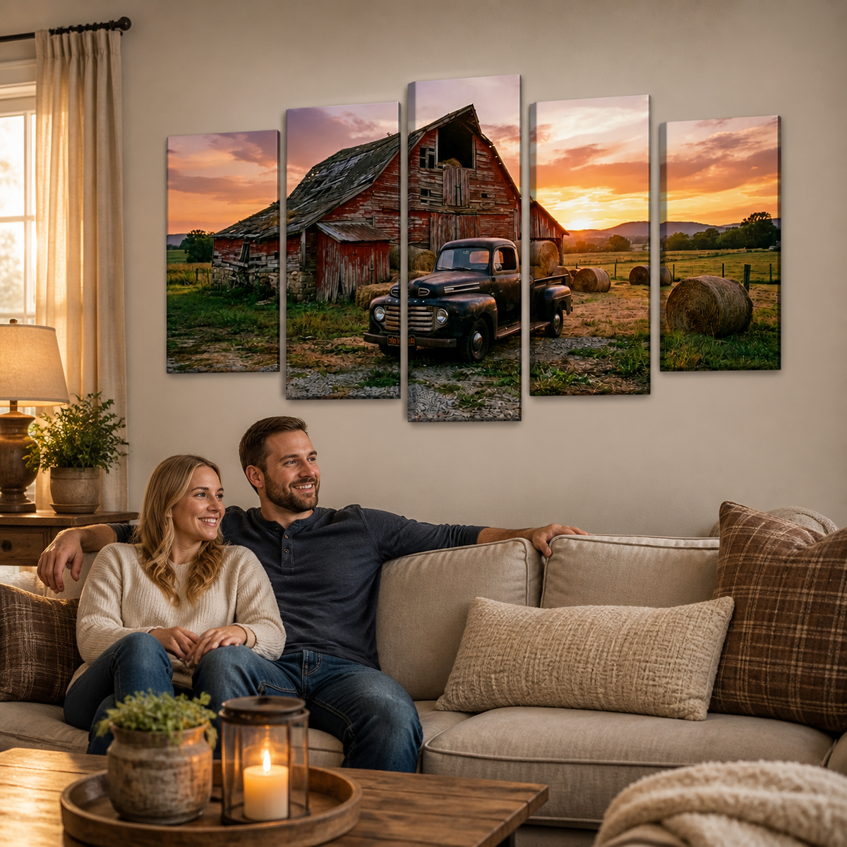 A couple relaxes on a beige sofa in a cozy living room, looking at a five-panel canvas wall art print depicting a rustic red barn, a vintage 1951 Ford F1  pickup truck, and hay bales at sunset.