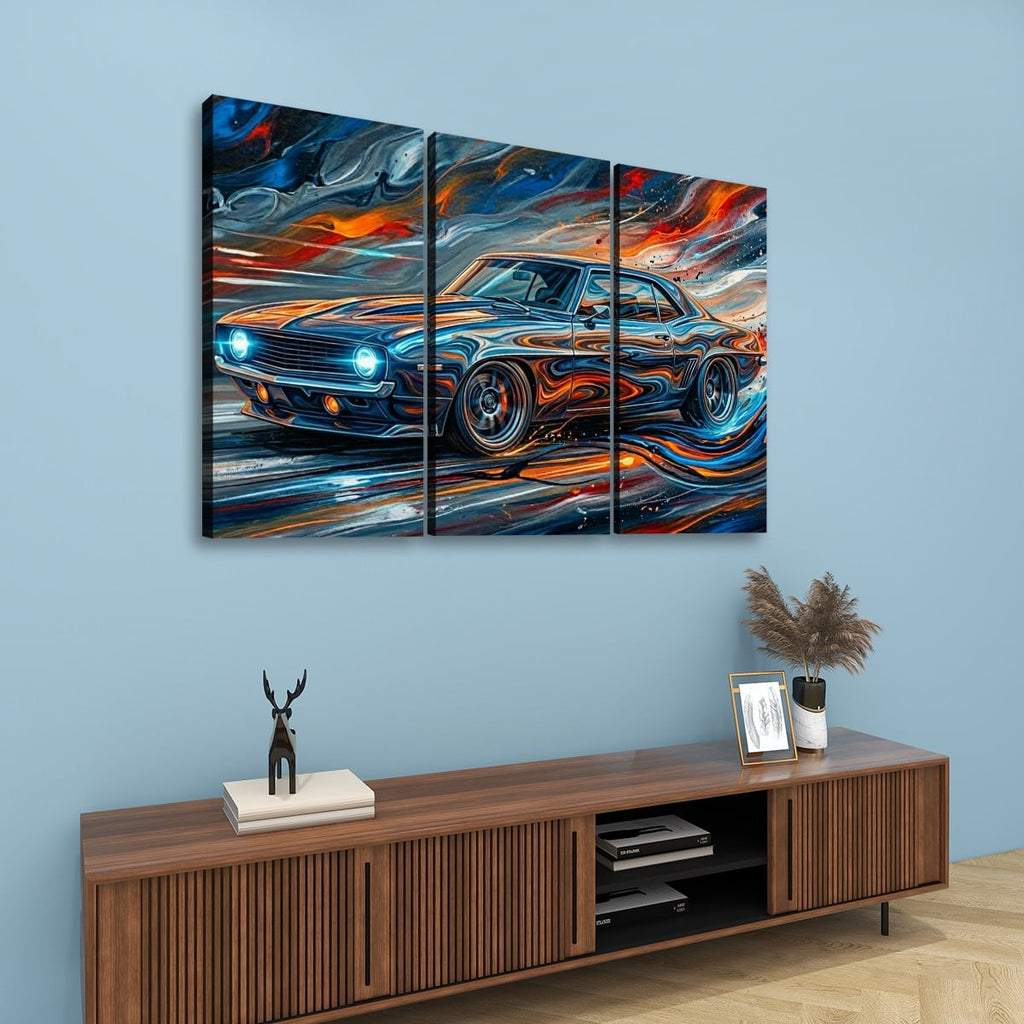 A three-panel canvas wall art set depicting a stylized 1969  Camaro blue sports car with swirling orange, red, and white brushstrokes, displayed above a wooden console table against a light blue wall.
