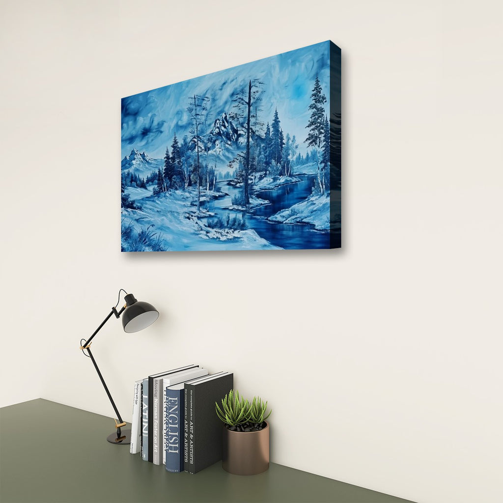 A rectangular wall art print showing a snowy blue winter landscape with trees and a river, displayed on a light wall above a desk with a lamp, books, and a small plant.