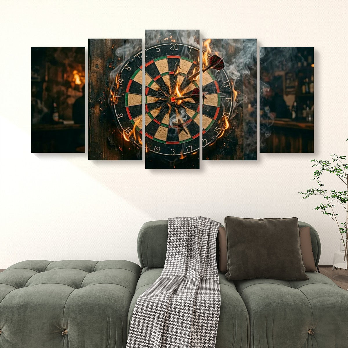 A 4-panel canvas wall art set depicting a burning dartboard with smoke and a dimly lit bar background, displayed on a white wall above a green tufted sofa with a throw blanket and pillow.