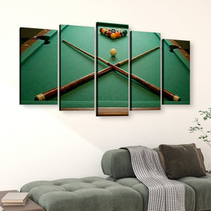 A 5-panel canvas wall art set depicting a green pool table with crossed pool cues and a racked set of billiard balls, displayed on a white wall above a green sofa in a living room setting.