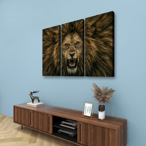 A three-panel canvas wall art set depicting a roaring lion's face and mane, displayed on a light blue wall above a wooden media console with decorative items.