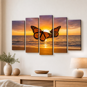 A five-panel canvas wall art set depicting a monarch butterfly in flight over an ocean sunset, displayed on a white wall above a wooden console table with a lamp and decorative objects.