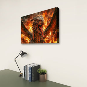 A rectangular wall art print showing a fiery dragon with wings spread, displayed above a desk with books, a lamp, and a small plant against an off-white wall.