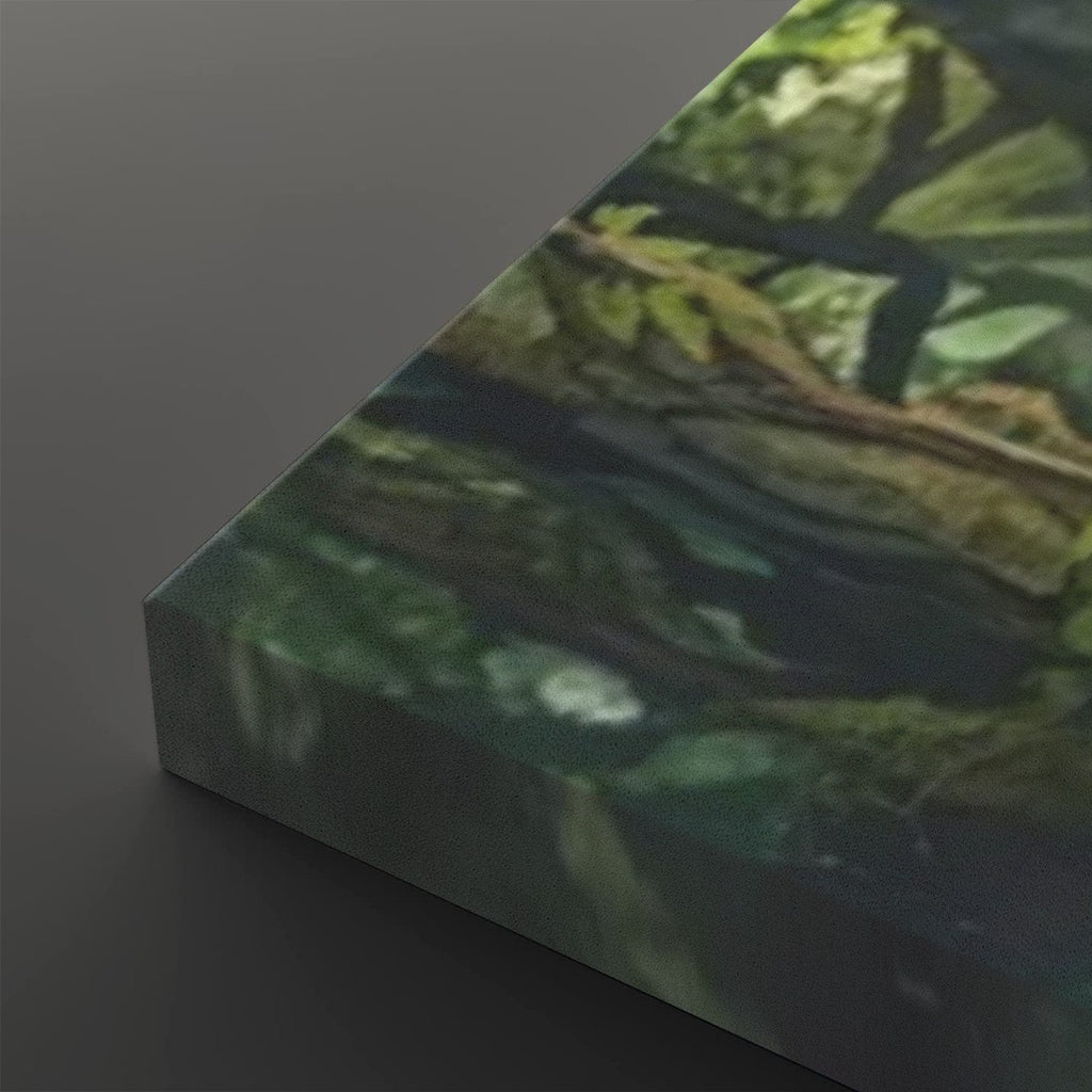 A close-up of a rectangular canvas or print showing a forest scene with green foliage and dark branches, photographed against a dark gray background.