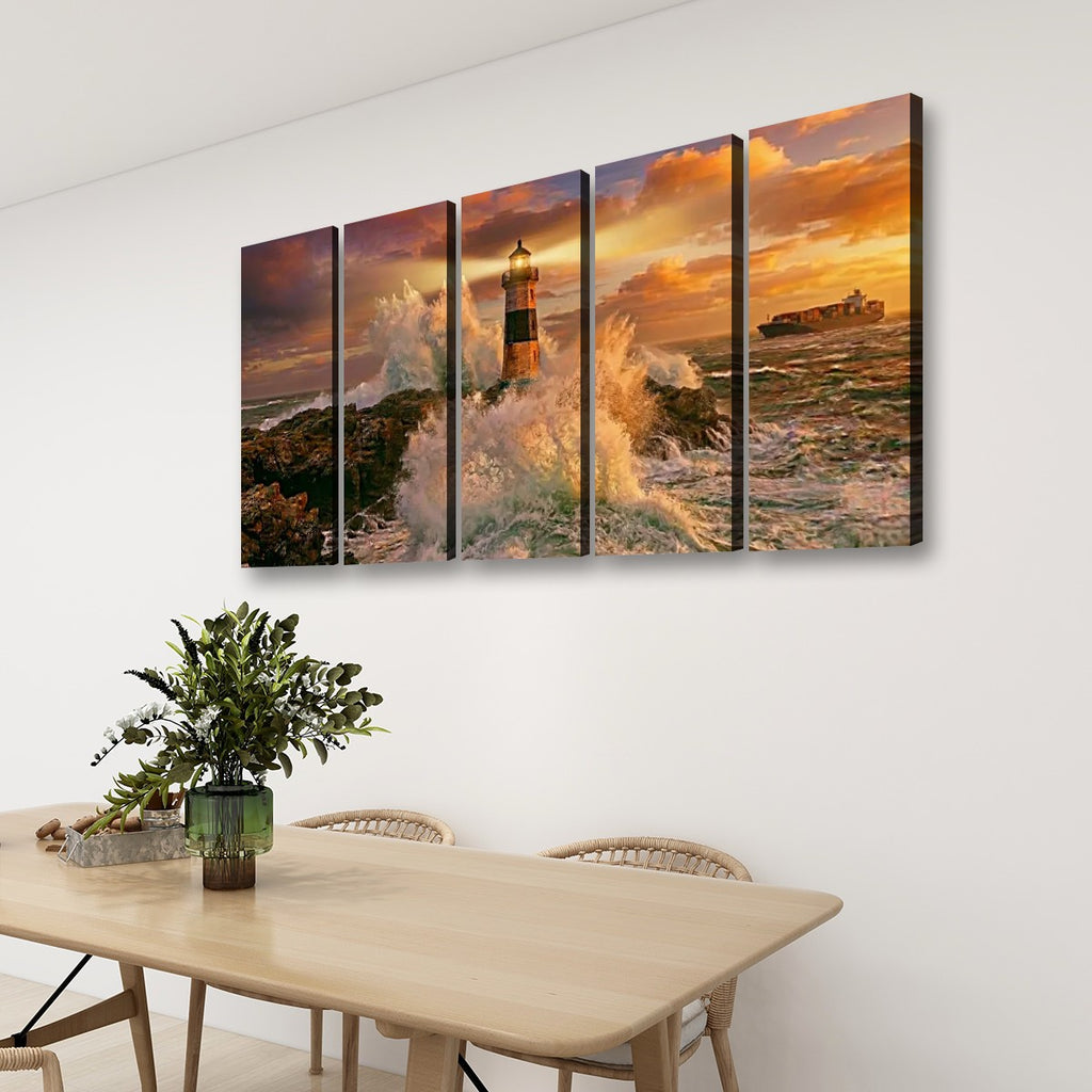 A four-panel canvas wall art set depicting a dramatic lighthouse scene with ocean waves and a golden sunset, displayed on a white wall above a dining table with chairs and a plant.