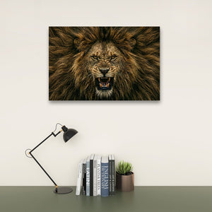 A rectangular wall art print showing a close-up lion face with an open mouth, displayed above a desk with a black lamp, books, and a small succulent against a light wall.