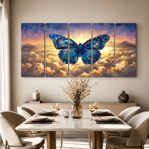 A five-panel canvas wall art set depicting a large blue butterfly over a glowing mountain range and golden clouds, displayed above a dining table in a modern dining room setting.