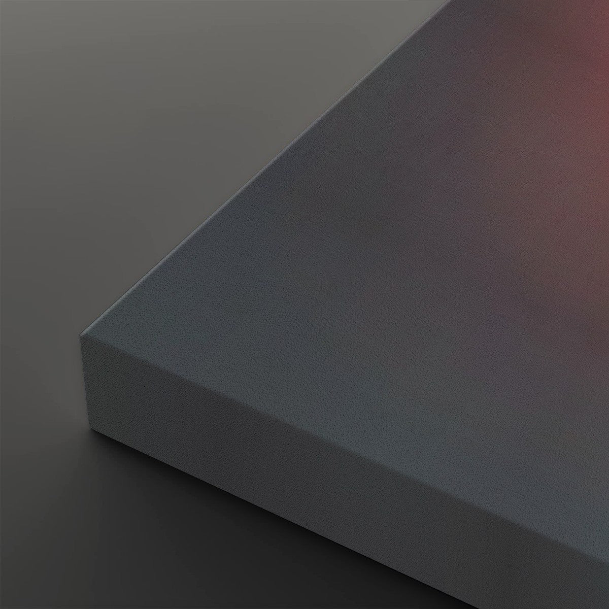 A close-up of a matte gray rectangular block or panel corner, shown against a matching dark gray background with a soft warm red glow in the upper right.