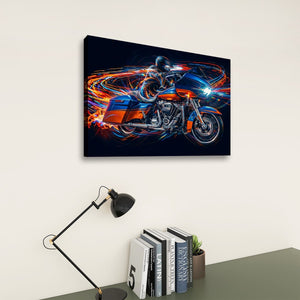 A rectangular wall art print showing a stylized Road Glide type motorcyclist in motion with vivid blue, orange, and white light streaks on a dark background, displayed above a desk with books and a lamp in a room setting.