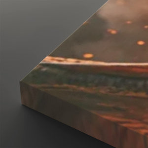 A close-up of a rectangular canvas or print showing an abstract landscape-like scene with warm brown, orange, and muted green tones, photographed against a dark gray background.