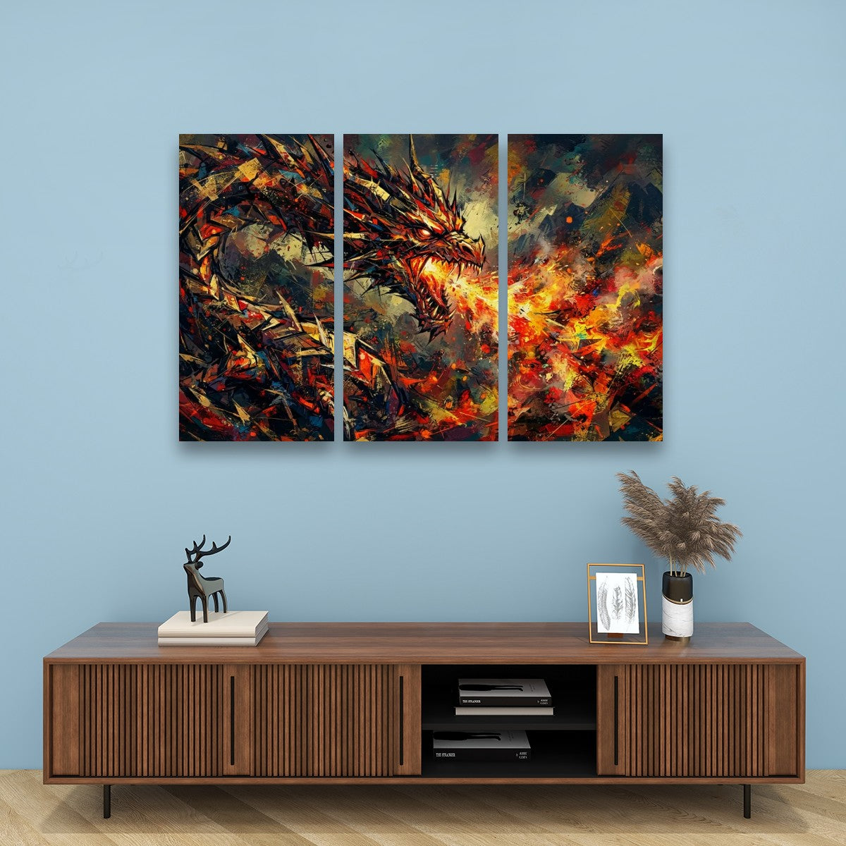 A three-panel canvas wall art set depicting a fiery dragon in an abstract, textured style, displayed on a light blue wall above a wooden console table.