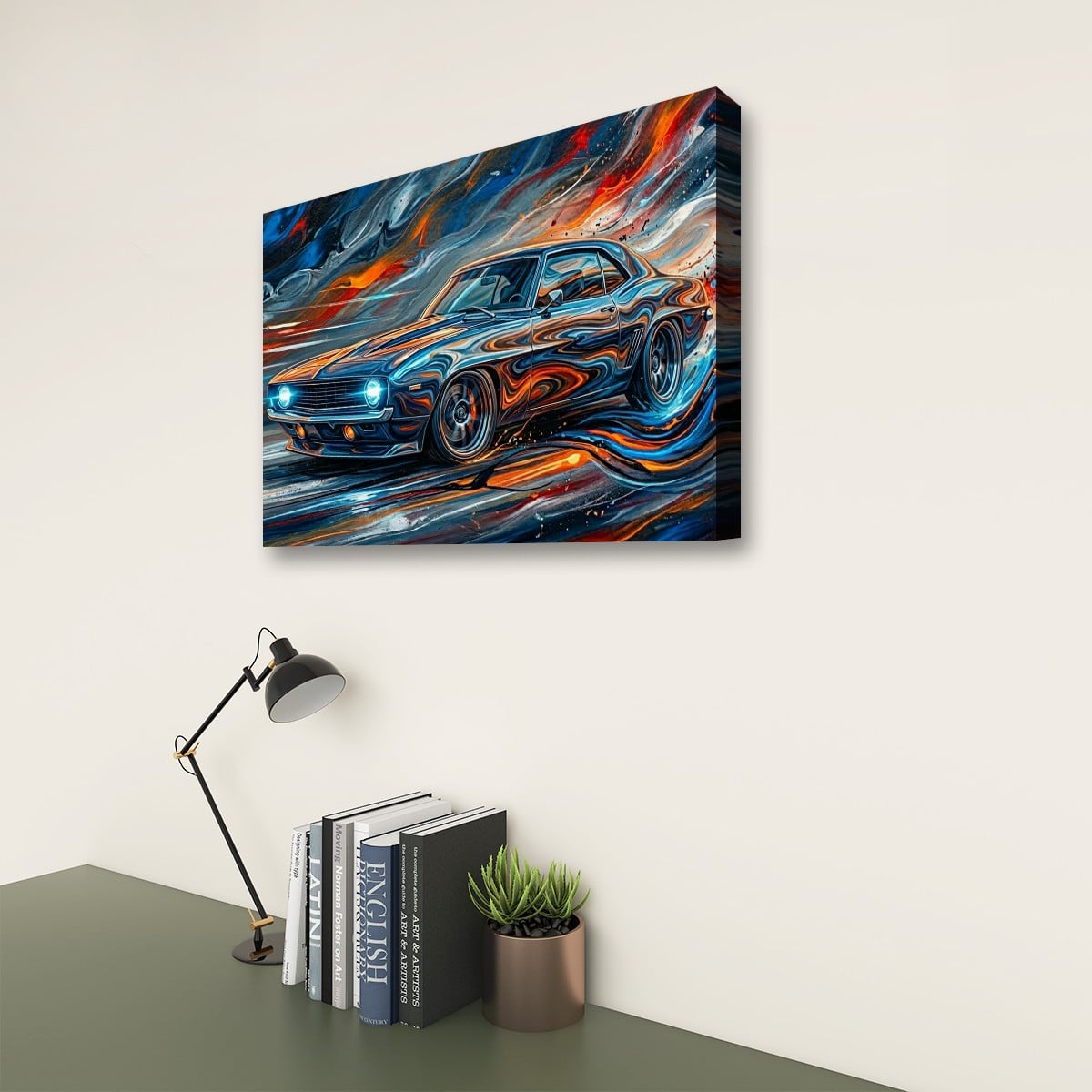 A rectangular wall art canvas showing a stylized blue 1969  Camaro muscle car with swirling orange, red, and blue brushstrokes, displayed above a desk with books, a lamp, and a small plant in a real interior setting.