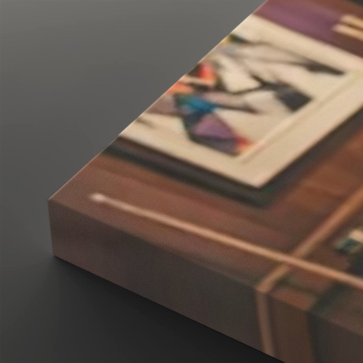 A close-up angled view of a rectangular product, likely a box or package, with a printed surface showing a blurred indoor scene. The visible object is predominantly brown with a dark gray side edge, photographed against a dark gray background.