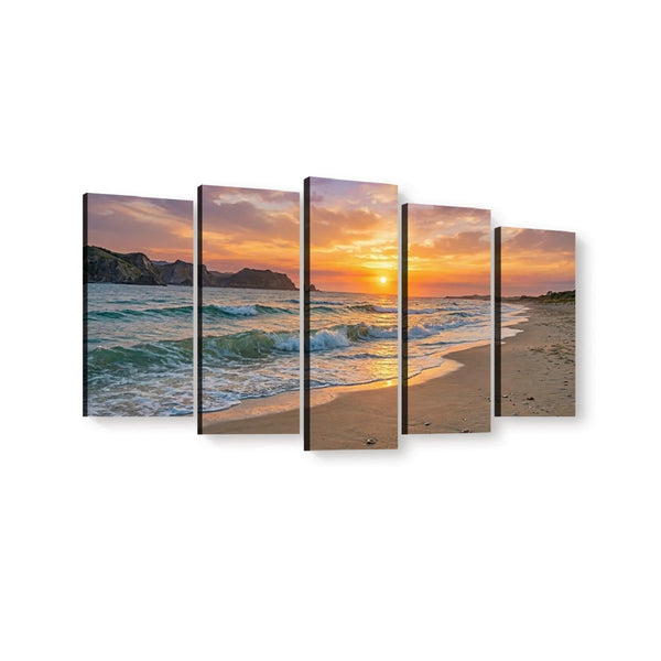 Five-panel canvas wall art showing a beach sunset with ocean waves, sandy shore, and rocky cliffs, displayed against a plain white background.
