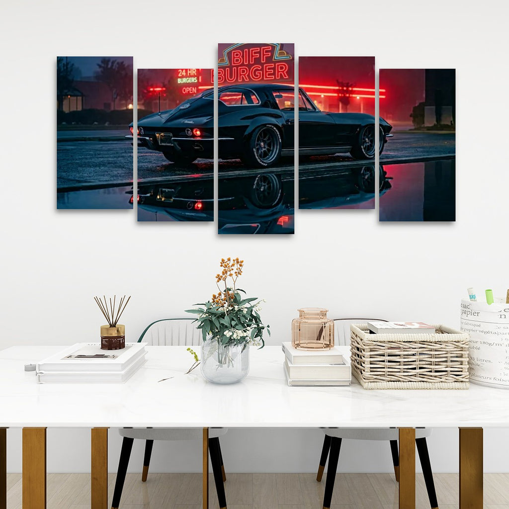A 5-panel canvas wall art set depicting a classic black 1963 Split Window Chevy Corvette night with red neon signs and a wet reflective street, displayed on a white wall above a modern white dining table with books and a vase.