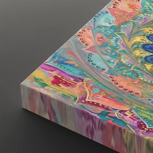A close-up angled view of a square canvas print showing a colorful abstract mandala design with swirling teal, pink, yellow, purple, and blue patterns on a dark gray background.