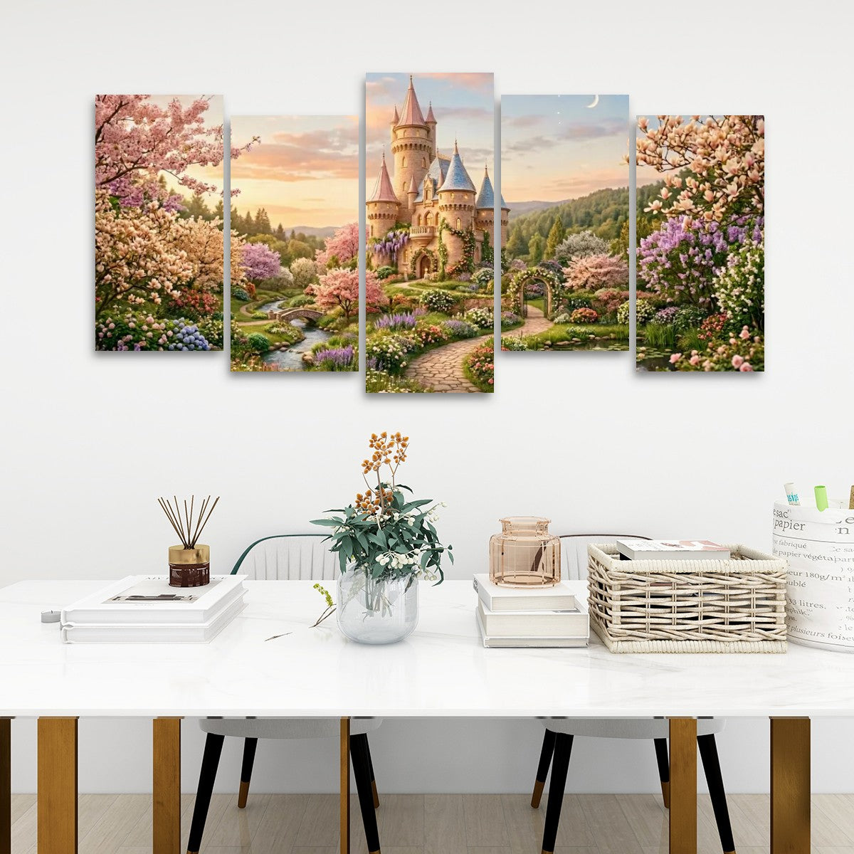 A five-panel canvas wall art set depicting a fantasy castle in a floral landscape, displayed on a white wall above a styled dining table with books, a vase, and a basket.