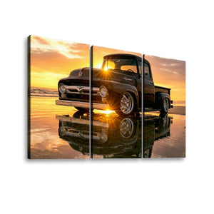 Three-panel canvas wall art showing a black vintage  1956 Ford  F-100 pickup truck parked on wet sand at sunset, with the truck and its reflection mirrored in the water. The panels are displayed against a plain white background.