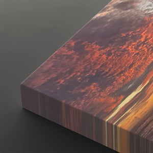 A close-up of a rectangular canvas or print showing an abstract landscape-like scene with swirling orange, red, brown, and cream tones, photographed on a dark gray background.