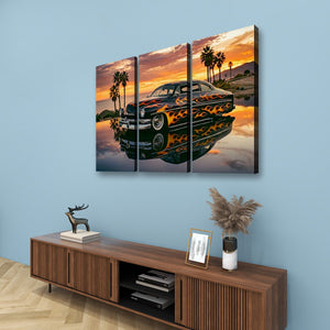 A three-panel canvas wall art print depicting a black classic car with orange flames, parked in front of palm trees at sunset, displayed on a light blue wall above a wooden console table with decorative items.